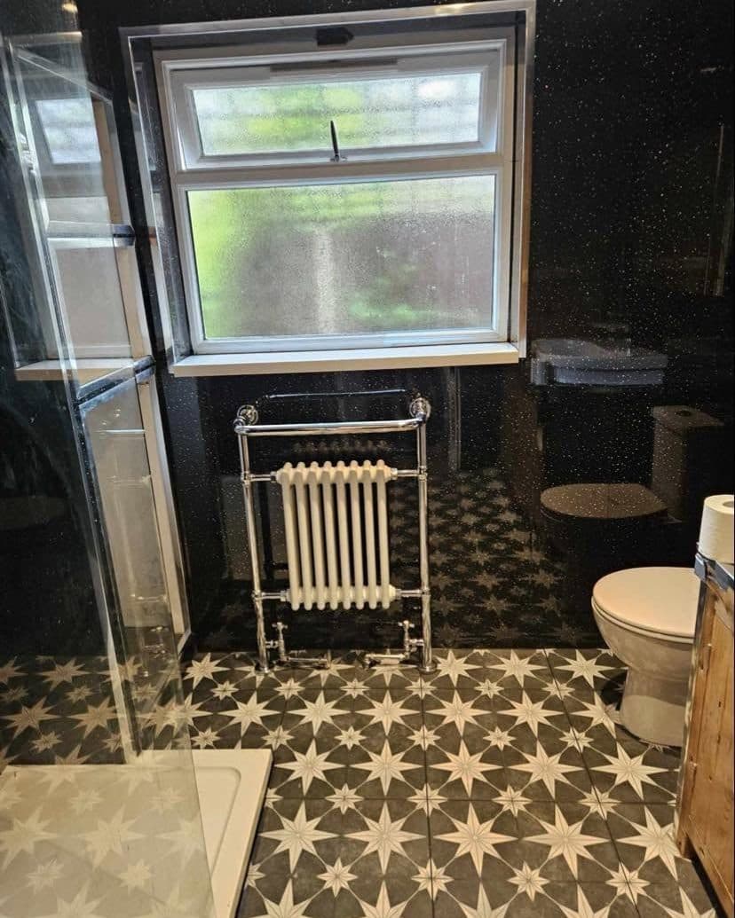 Bathroom with black and white star-pattern floor tiles and a traditional radiator