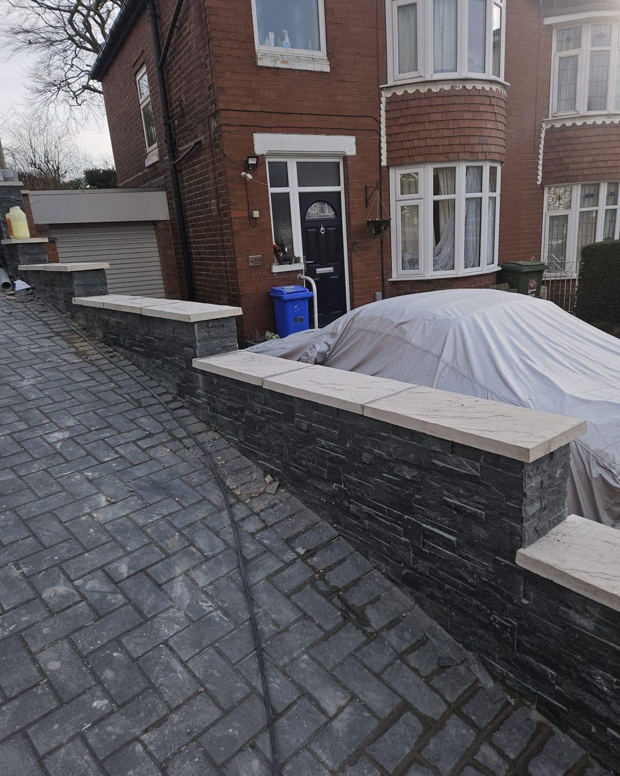 Charcoal block-paved driveway alongside a new slate-clad garden wall