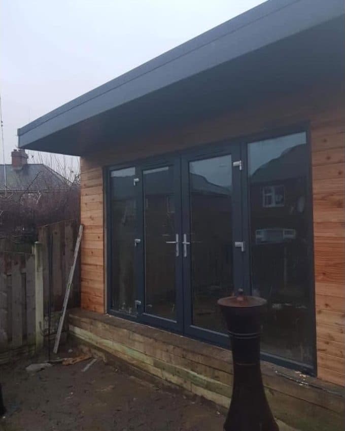 Timber-clad garden room with grey French doors, built by CS Construction