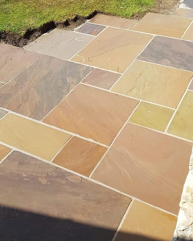 Newly laid Indian sandstone patio beside a lawn
