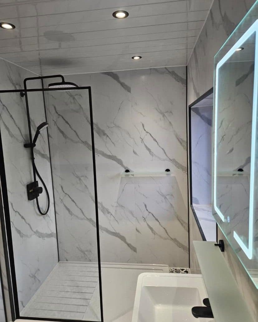 Shower room with marble-effect wall panels, a black-framed shower screen and an LED mirror